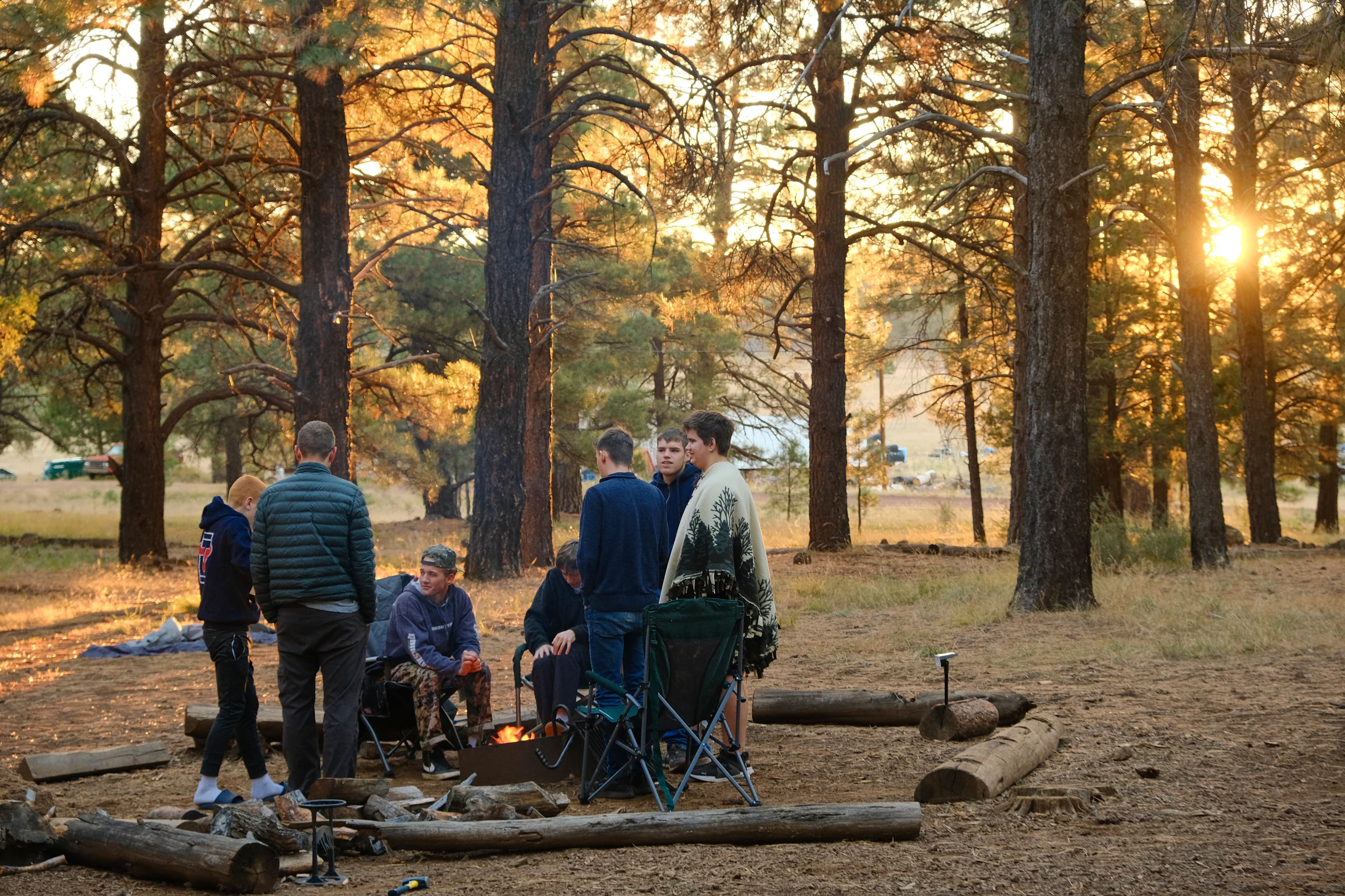 Young men around campfire in forest